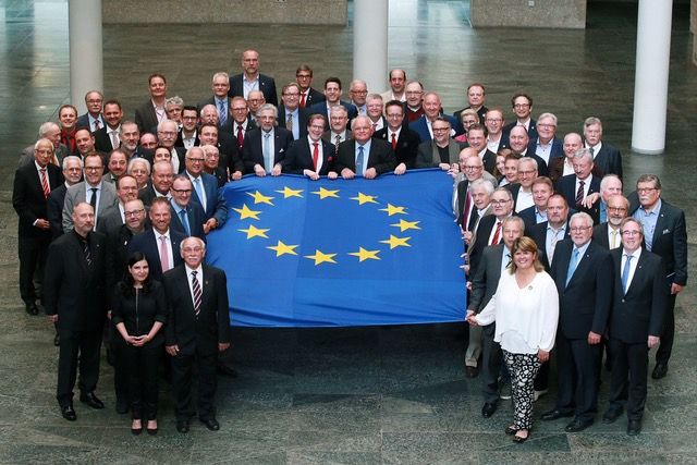 Präsident Michael Jung hält zusammen mit anderen Gesellschaftspräsidenten die Europaflagge im Kölner Rathaus